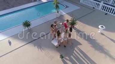 夏天，在昂贵的节日里，穿着泳衣的<strong>活泼活泼</strong>的女孩正在游泳池附近跳舞和喝酒